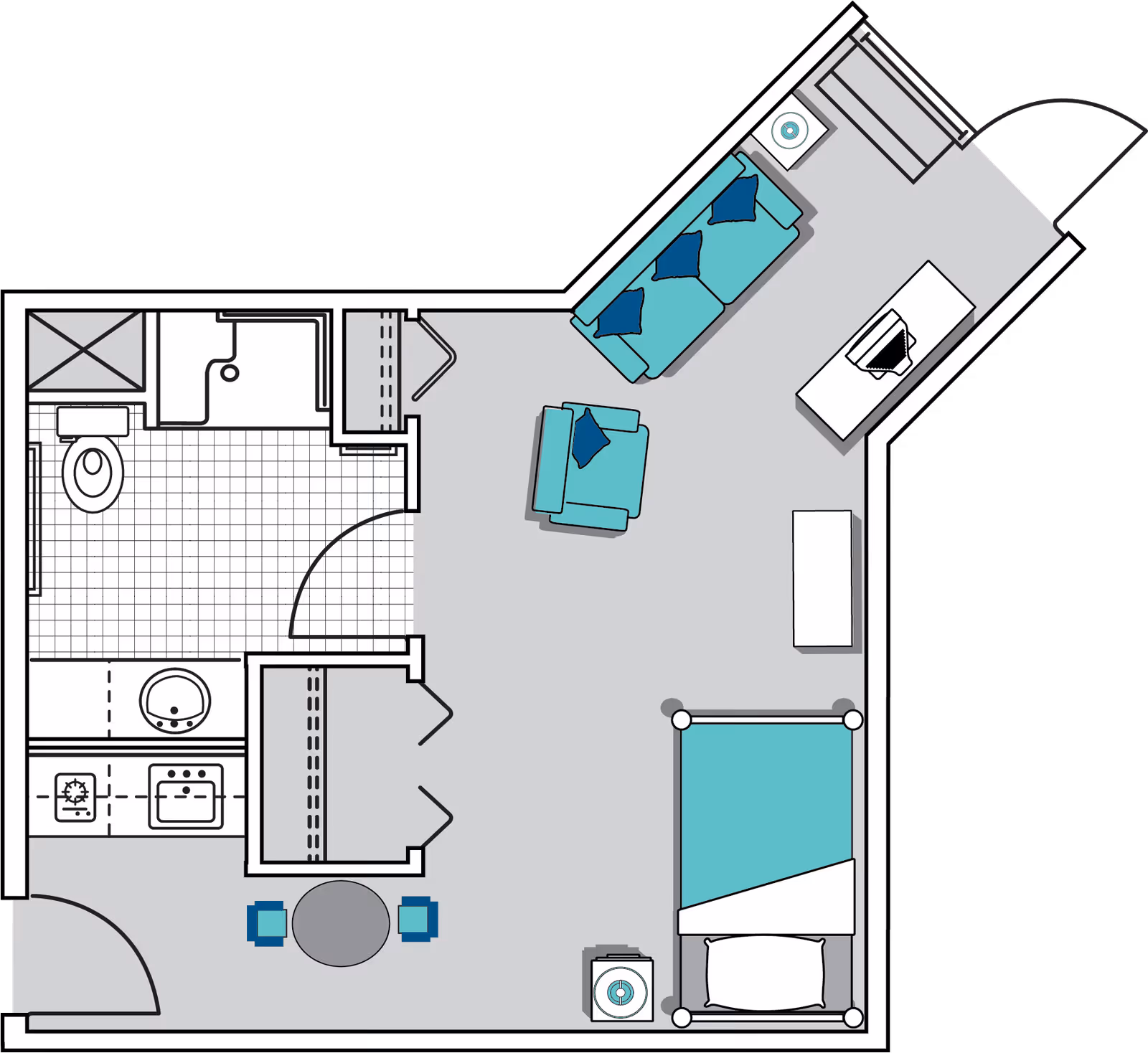Floor plan of a senior living unit at Oaks at Tucker showing a combined living and sleeping area with a bed, armchair, sofa, side tables, and a desk. The unit also includes a kitchen area with a stove and sink, a bathroom with a toilet and shower, and a small dining area with a round table and two chairs.