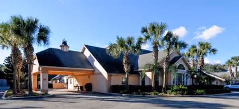 Exterior view of Brookdale DeLand senior living facility with palm trees and a driveway entrance.