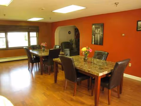 Bright communal dining room in a senior facility with marble tables and flowers.
