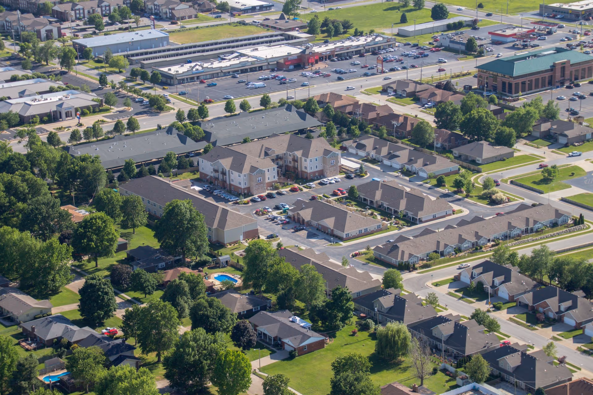 Aerial view of a suburban area showing a senior living facility named The Fremont Senior Living surrounded by residential houses, trees, parking lots, and nearby commercial buildings.