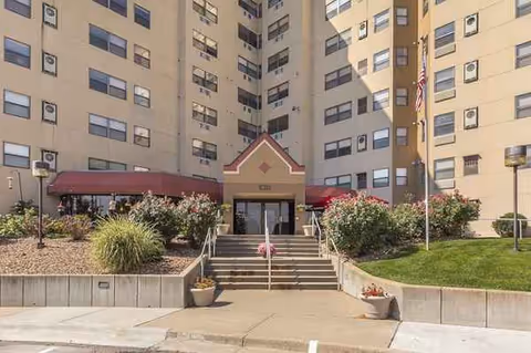 Exterior view of Victory Hills Senior Living Community entrance with stairs and greenery.