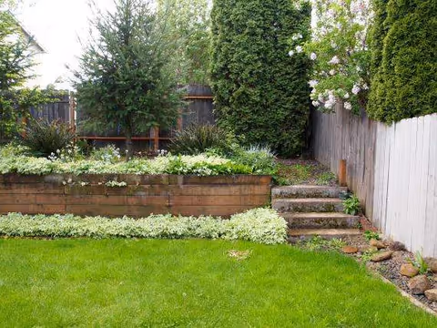 Backyard garden at Sunshine Care Adult Family Home with raised beds, stairs, and a wooden fence.