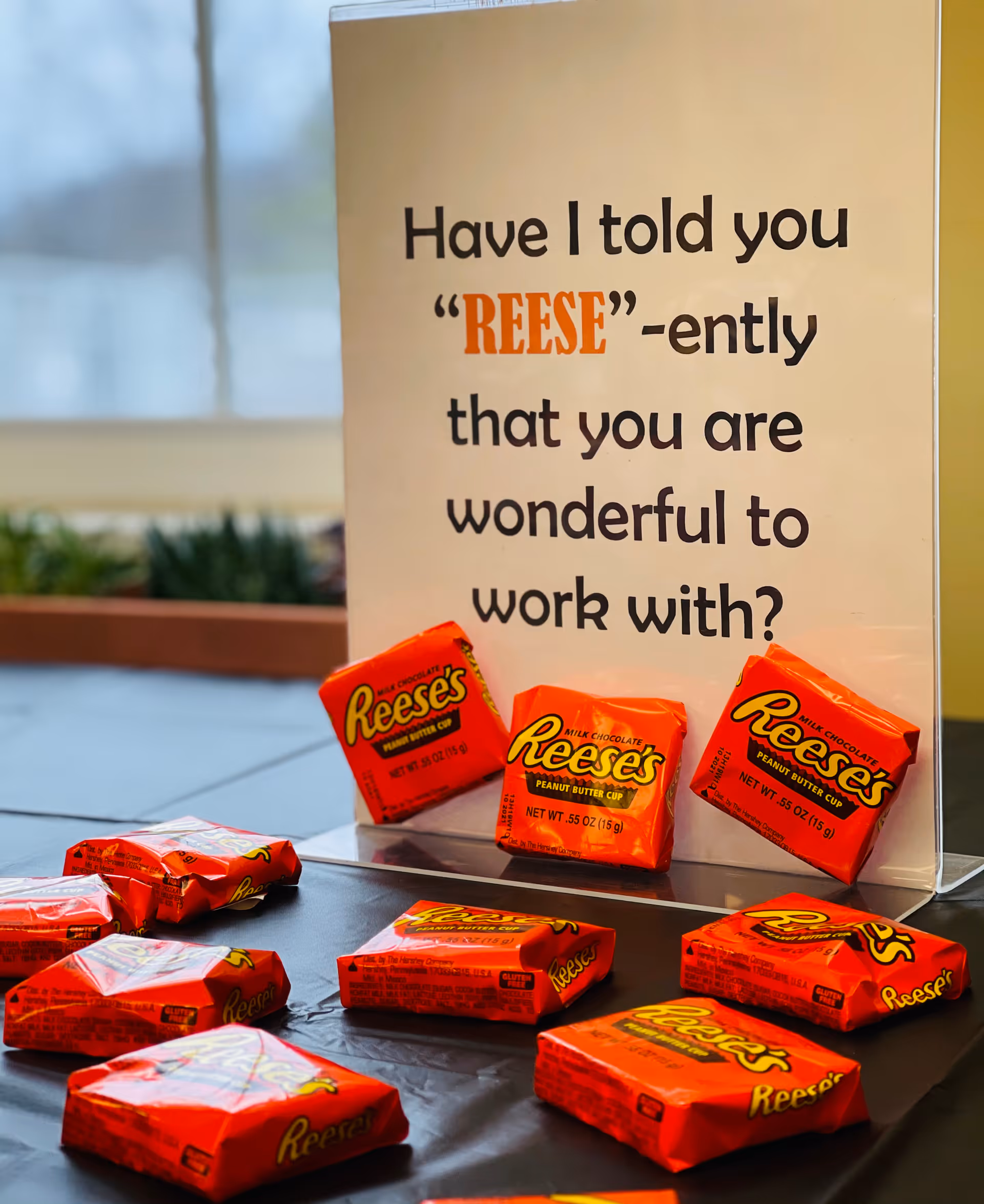 Table display of wrapped Reese's peanut butter cups arranged in front of a sign that says "Have I told you 'REESE'-ently that you are wonderful to work with?"