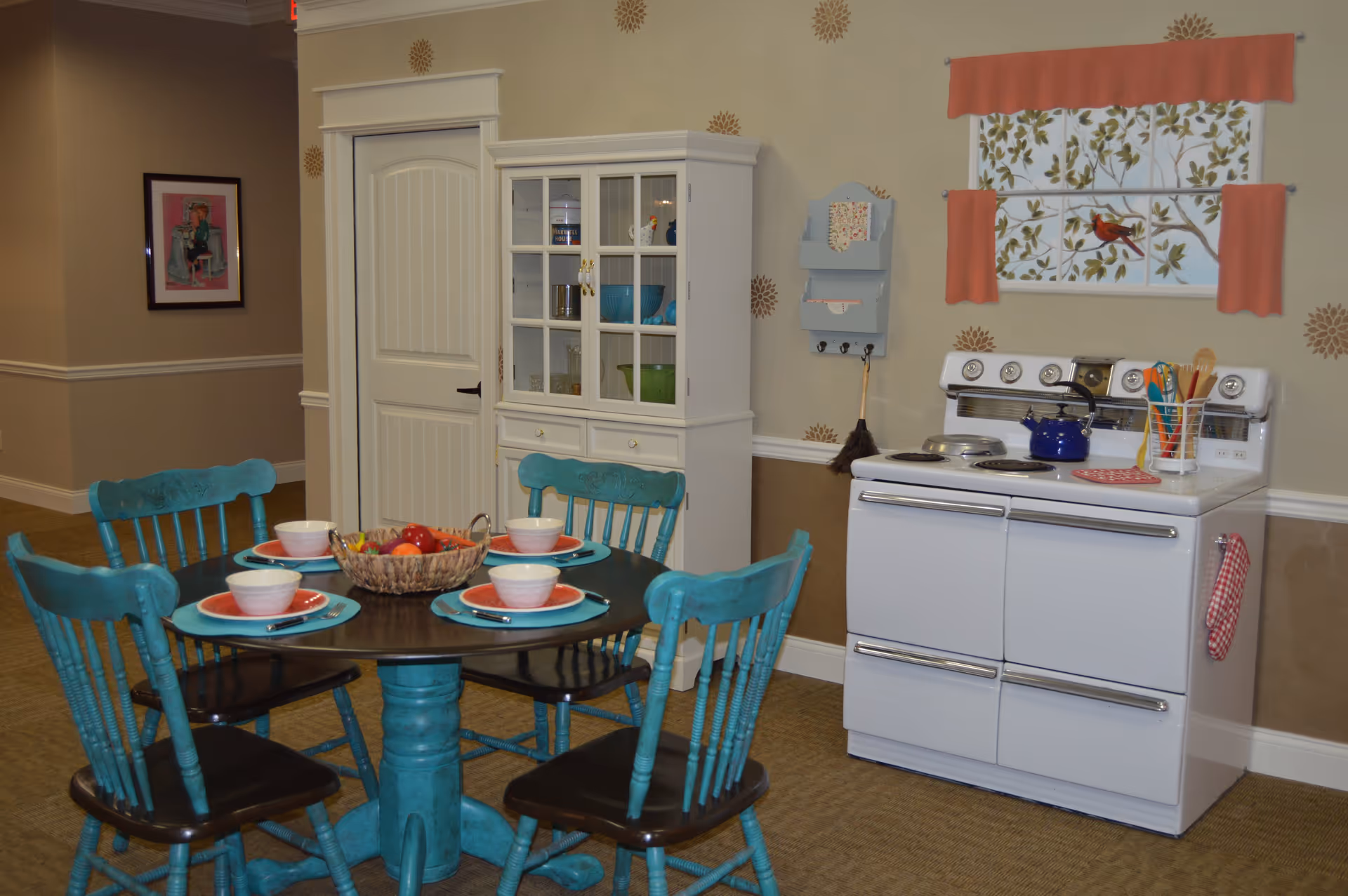 Small dining area with a round table set for four and a vintage white stove against a decorated wall.