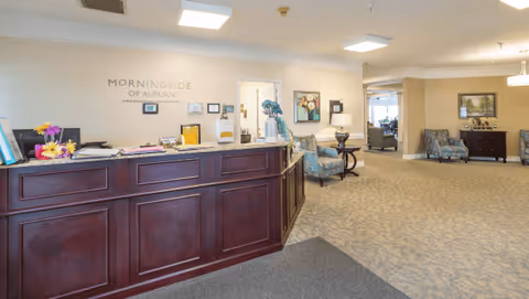 Reception desk and lobby of Morningside of Auburn with seating, artwork, and signage on the wall.