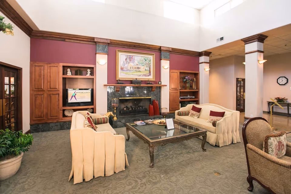 Elegant common lounge with sofas around a glass coffee table, a fireplace, built-in shelving and high skylight ceilings.