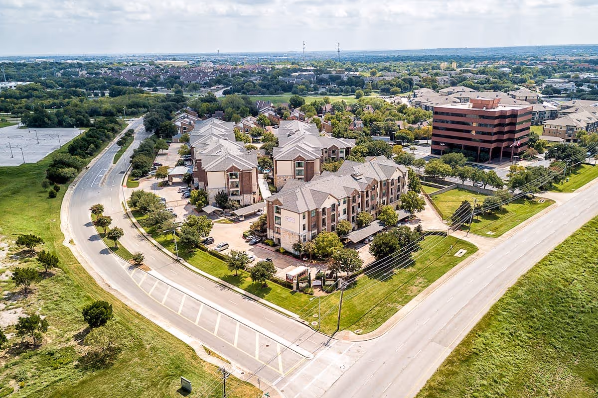 Aerial view of the Conservatory At North Austin senior living complex with multiple connected buildings, parking areas, and surrounding roads and green space.