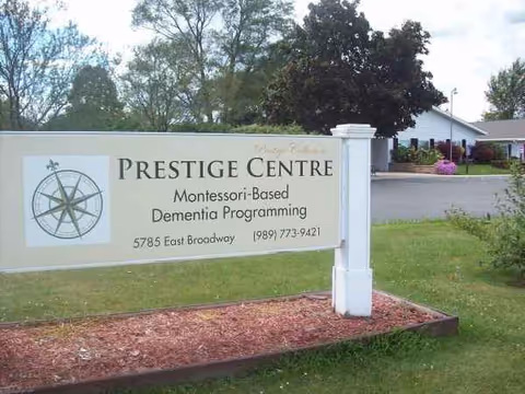 Exterior view of a facility sign reading Prestige Centre, with lawn and building in background.