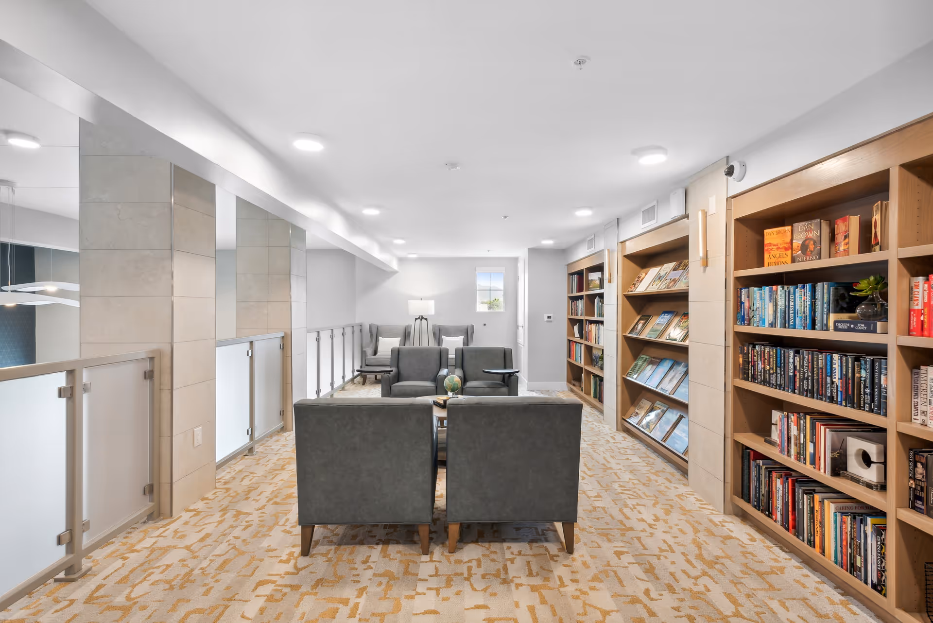 A bright communal reading/lounge area with bookshelves along the right wall and seating arranged around a coffee table.