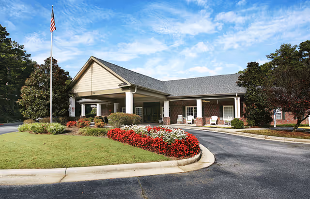 Exterior view of a senior living facility with a covered entrance and landscaped grounds.