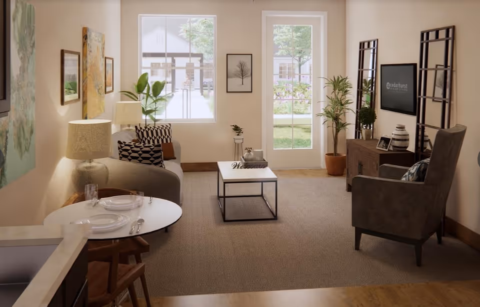 A cozy senior living room with a gray sofa adorned with patterned pillows, a small round dining table set for two, a coffee table with a 'Welcome' sign, an armchair, a TV mounted on the wall displaying the Cedarhurst Senior Living logo, and large windows and a glass door letting in natural light and showing a garden outside.