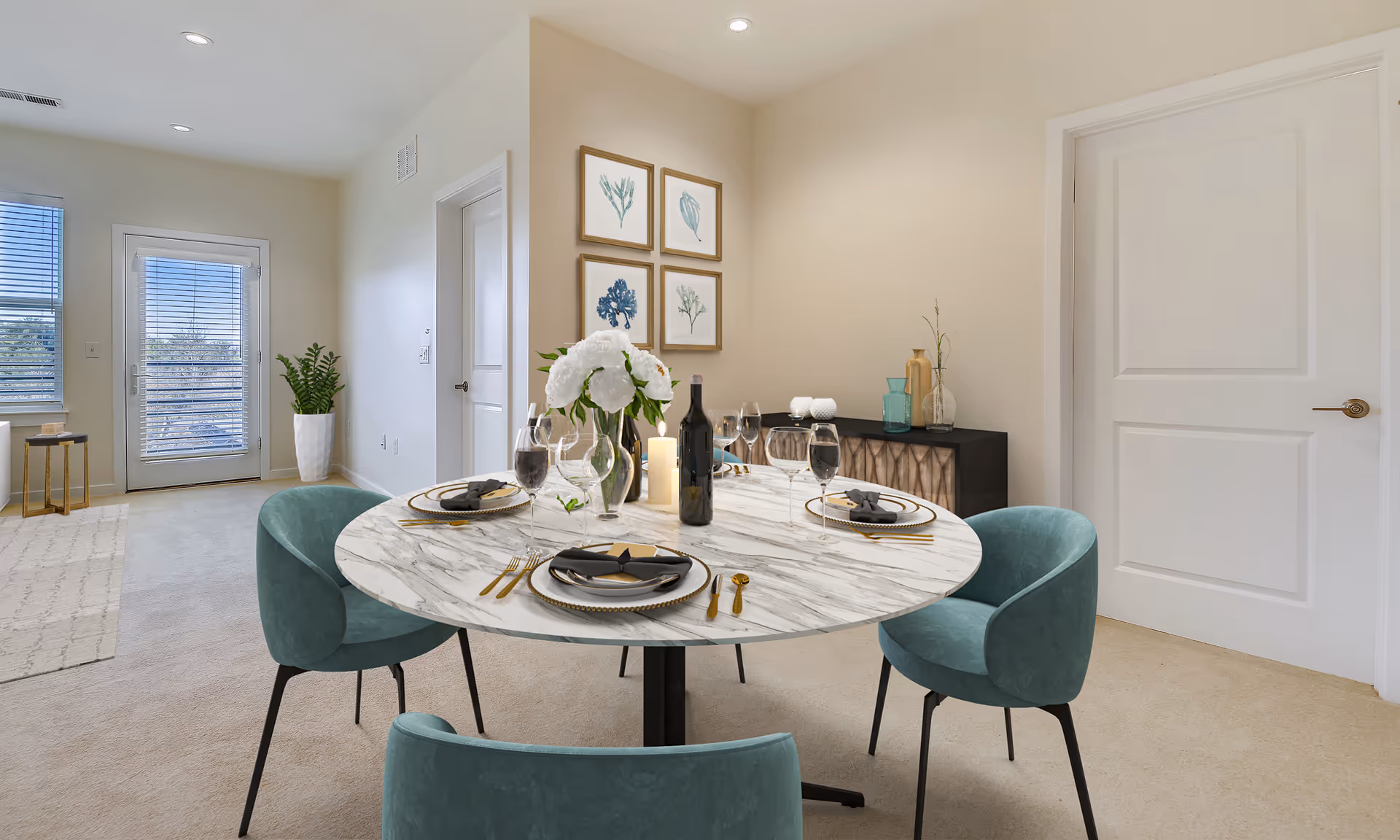Bright modern dining area with a round marble table set for four and teal upholstered chairs in a neutral apartment interior.