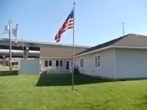Exterior view of a single-story building with an American flag on a green lawn