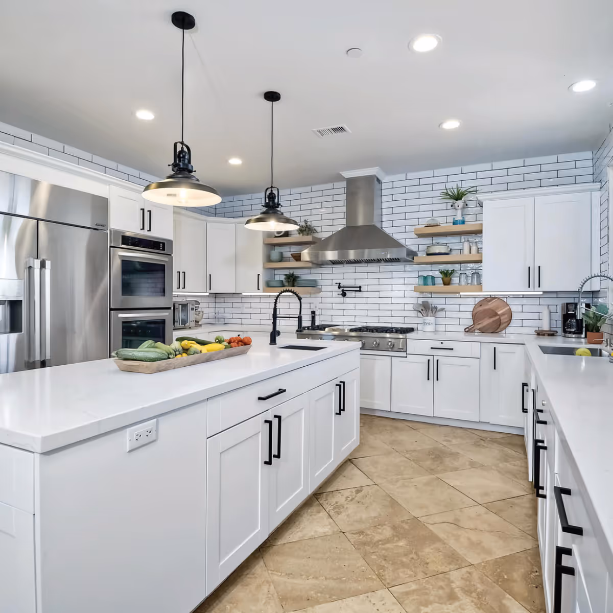 Bright modern white kitchen with a large island, stainless steel appliances, subway tile backsplash, open shelving and pendant lights.