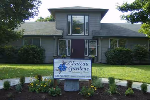 Front view of Chateau Gardens Memory Care building with landscaped sign and greenery.
