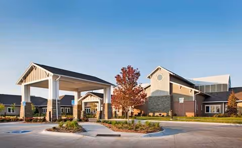 Senior living facility exterior with a covered entrance and landscaped parking area.