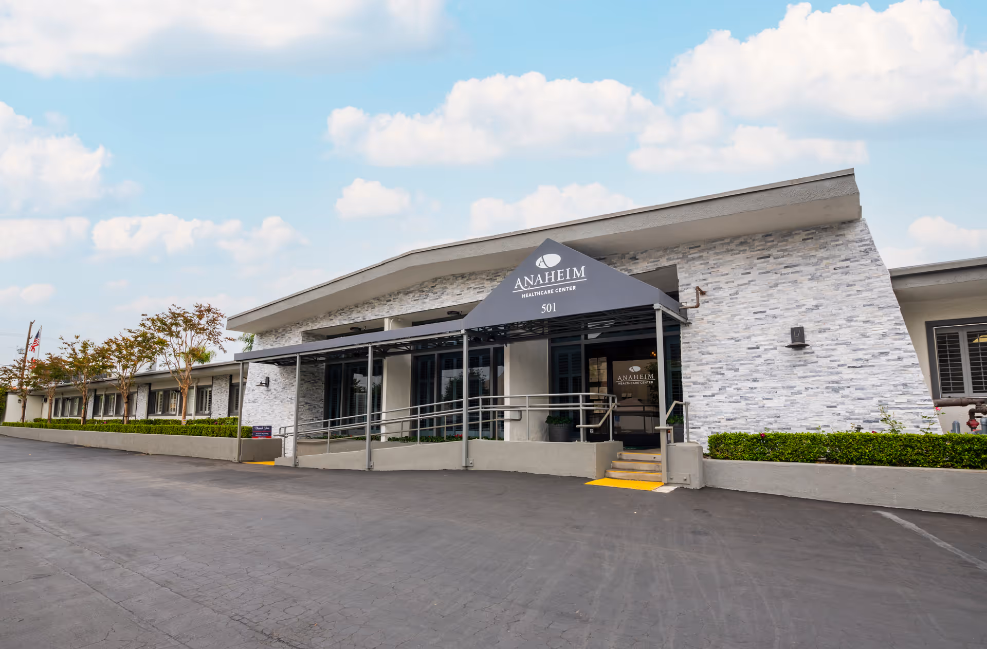Front entrance of the Anaheim Healthcare Center building with a covered awning, ramp, and steps.