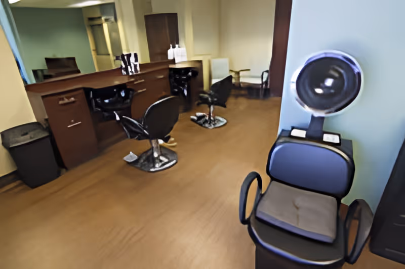 Small salon area with styling chairs, a hooded hair dryer, and a counter with mirrors.
