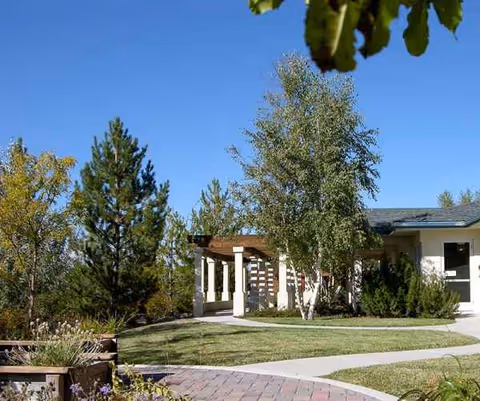 Exterior view of Arbors Memory Care facility with walkway and trees.