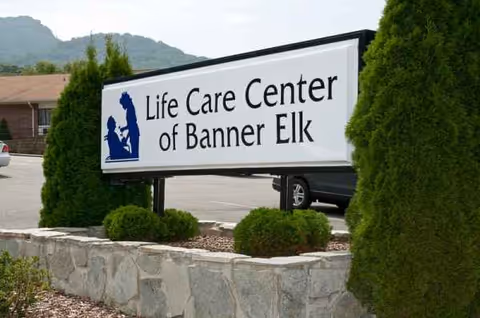 Exterior view of the Life Care Center of Banner Elk sign with surrounding shrubs and rocks.