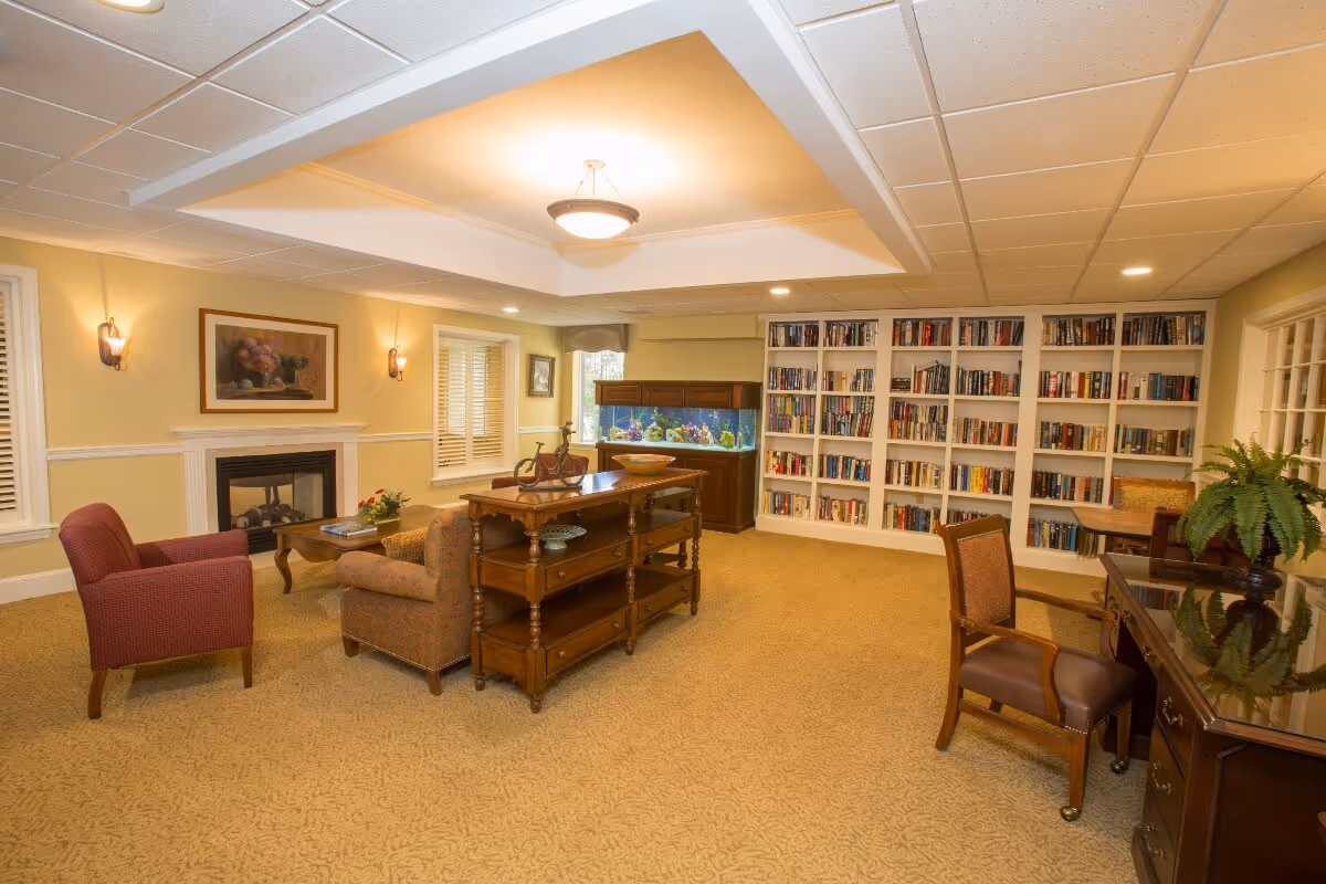 Well-lit communal living room with bookshelves, seating, a fireplace and an aquarium.