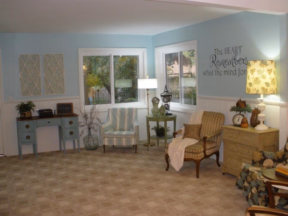 Bright living room with pastel blue walls, striped and upholstered armchairs, side tables, lamps, and decorative accents.