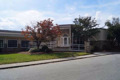 Front of a senior living facility featuring a ramp and manicured landscaping.