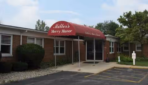 Exterior view of Miller's Merry Manor entrance with red awning and parking lot.