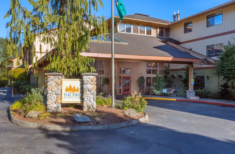 Front exterior of The Firs senior living facility with sign and entrance.