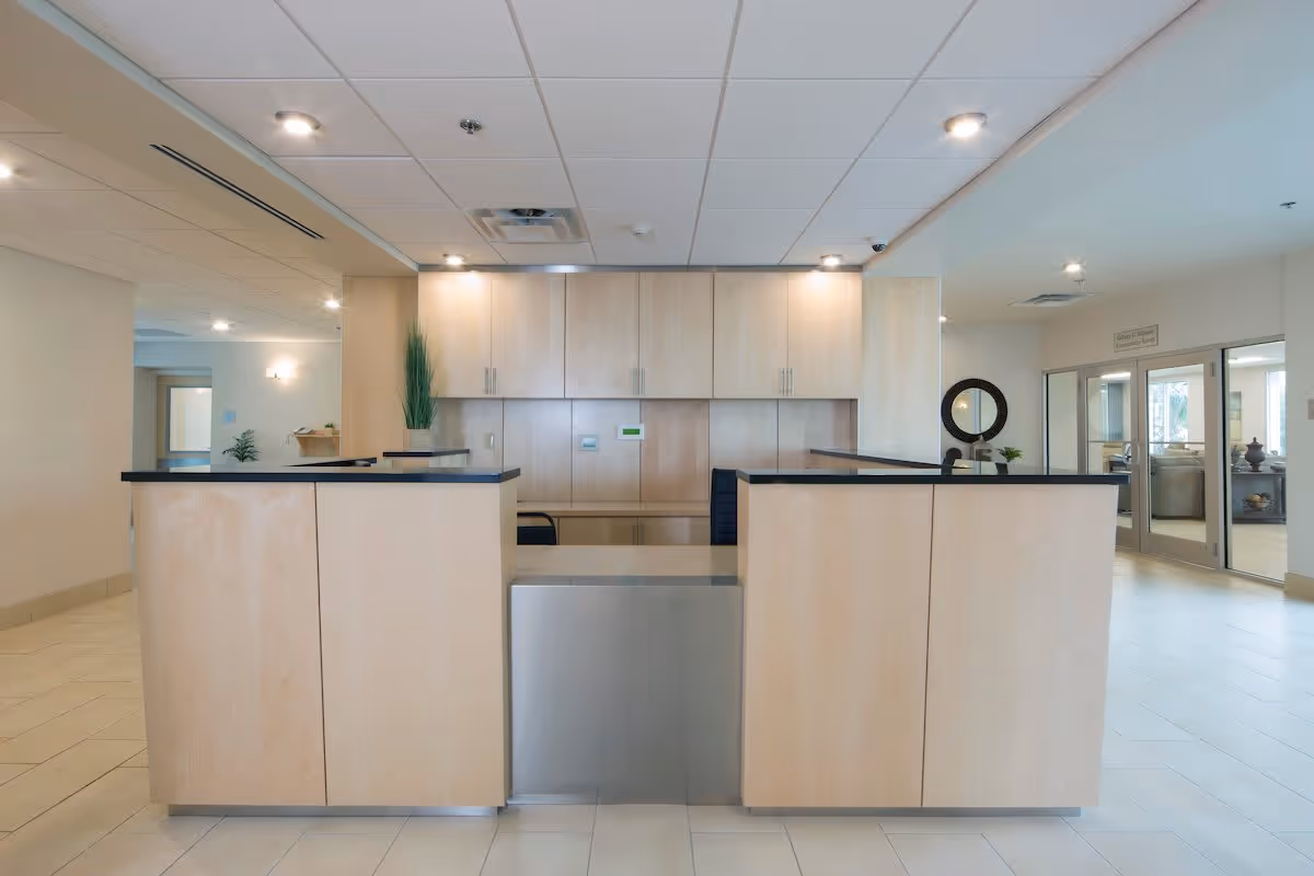 Reception desk and lobby area with light wood cabinetry, tiled floor, and ceiling lights.