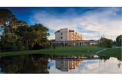 The Estates at Carpenters exterior: a multi-story building reflected in a pond with trees.