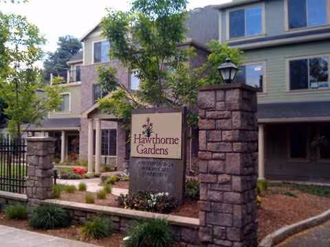 Stone entrance pillars frame Hawthorne Gardens Senior Living Community sign at the front of the building.