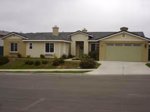 Beige, single-story senior living home with attached garage and neatly landscaped front yard.
