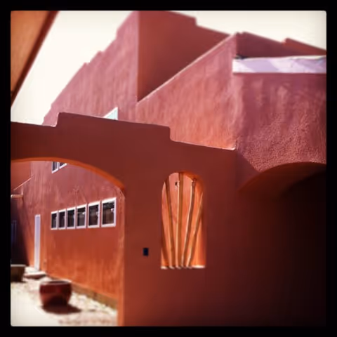 A red stucco building with curved arches and small rectangular windows.
