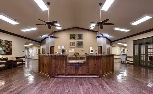 Spacious reception area with a large wooden front desk, vaulted ceiling with ceiling fans, and polished hardwood floors.