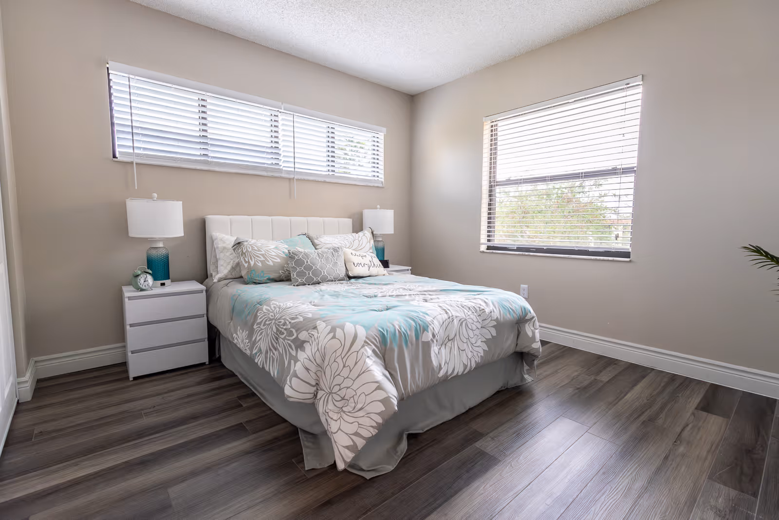 Bright, modern bedroom with a bed, two nightstands and large windows.