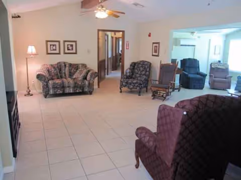 Spacious senior living common area with chairs, sofas, lamp, and ceiling fan.