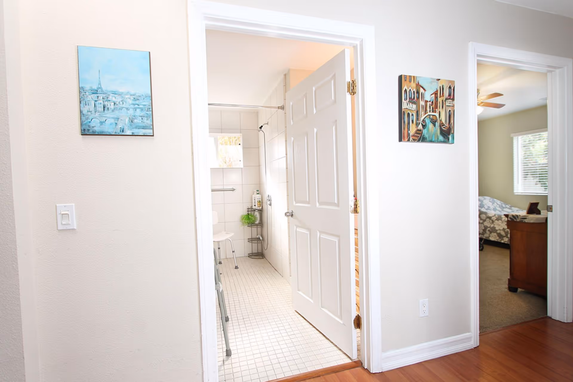 Open hallway showing a tiled bathroom through a doorway with a bedroom visible to the right.
