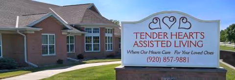 Exterior view of a brick Tender Hearts Assisted Living facility with a sign.