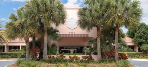 Exterior of Brookdale West Palm Beach with palm trees framing entrance.