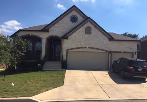Front view of a stone-faced, house-style facility with a two-car garage and a parked SUV.