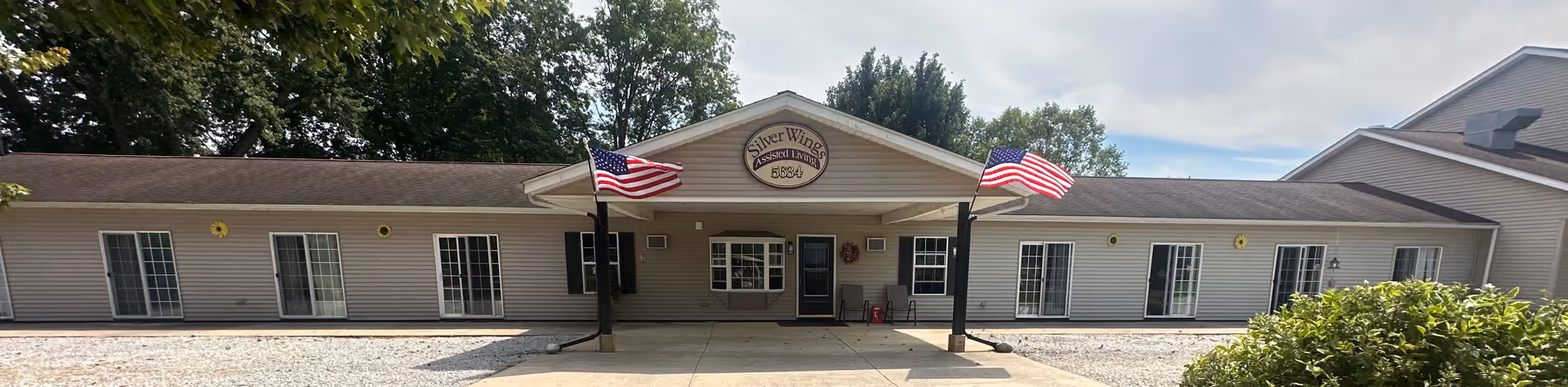 Exterior view of Silver Wings Assisted Living facility with American flags.