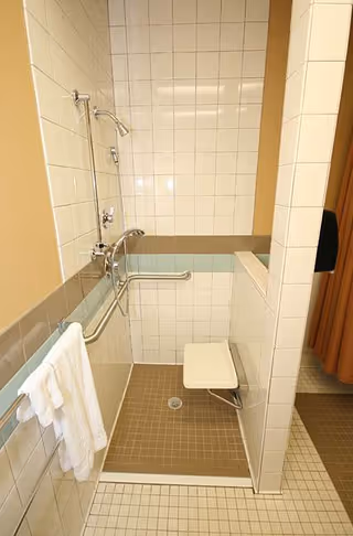 Accessible bathroom with a shower, grab bars, and a fold-down seat.