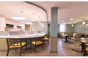 Spacious dining area with a curved service counter, multiple tables and chairs, and soft overhead lighting.