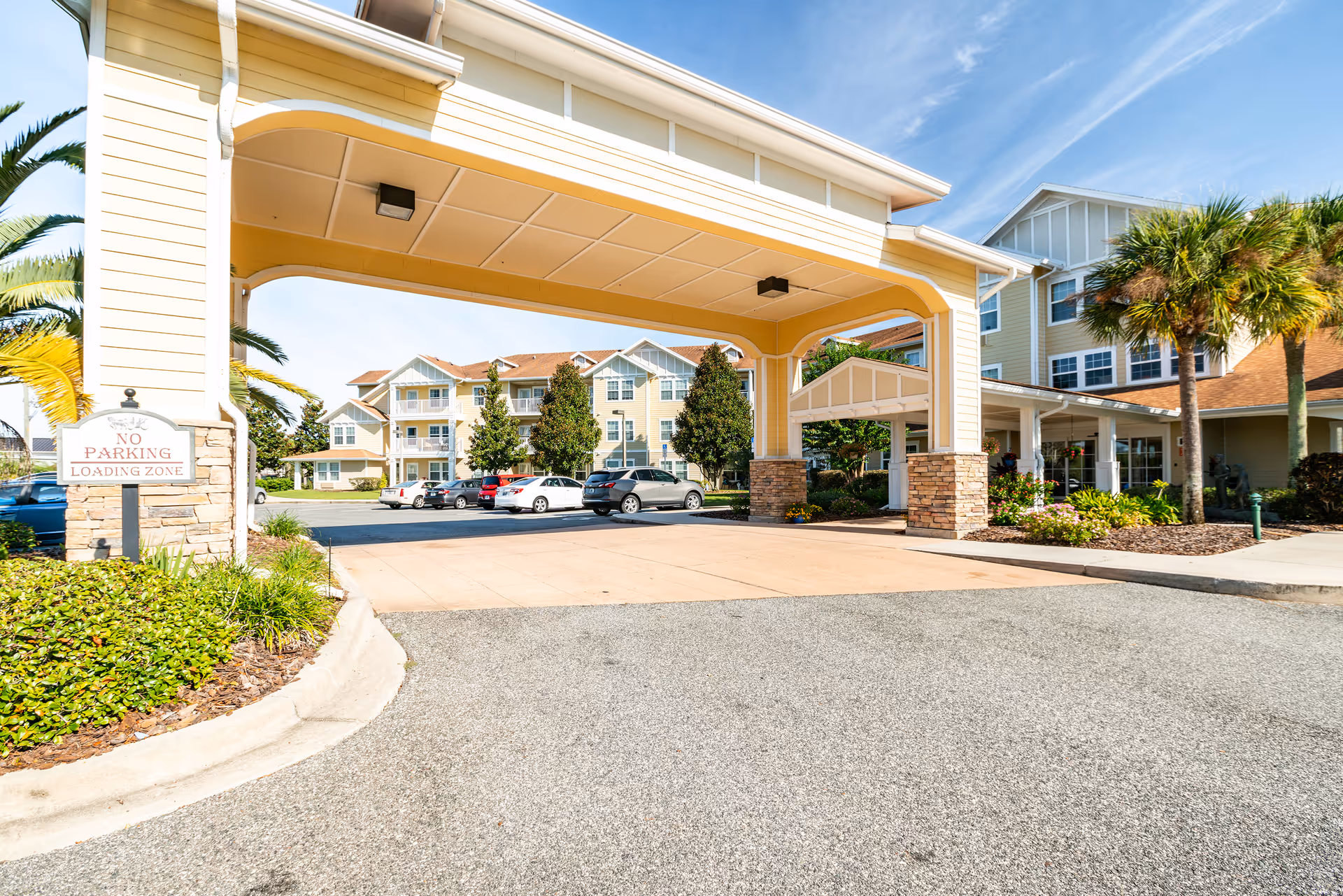 Front entrance of Steeplechase Gracious Retirement Living with a covered driveway and cars.