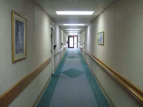 Long interior hallway in a senior living facility with wall art and handrails.