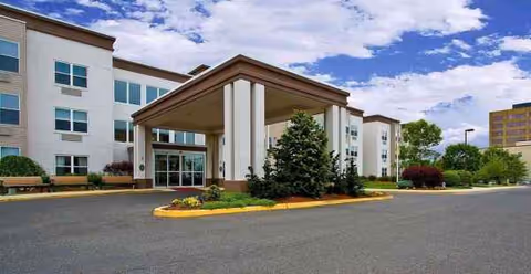 Exterior view of Seaton Voorhees senior living facility with a covered entrance and landscaped surroundings.