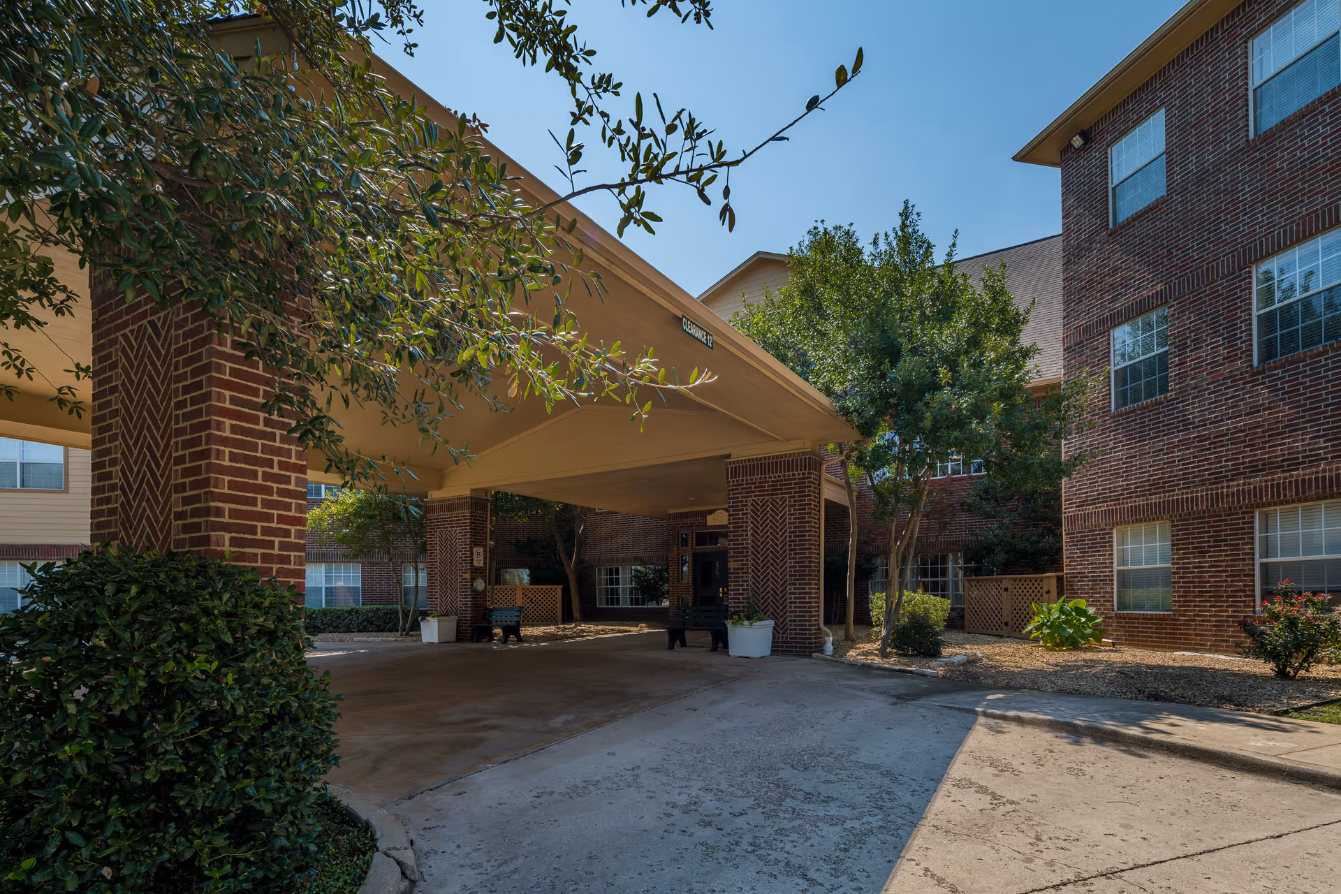 Brick senior living building with a covered entrance and drive-through drop-off area.