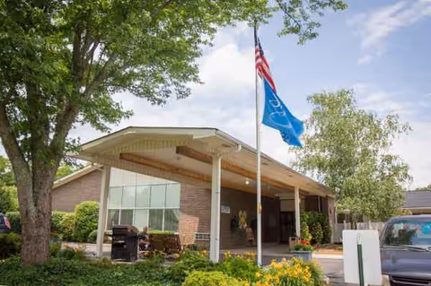 Front entrance of Standing Stone Care & Rehabilitation Center with flags, brick exterior, and landscaping.