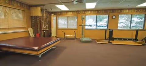 Indoor senior living exercise room with mats, balance boards, and gym equipment.